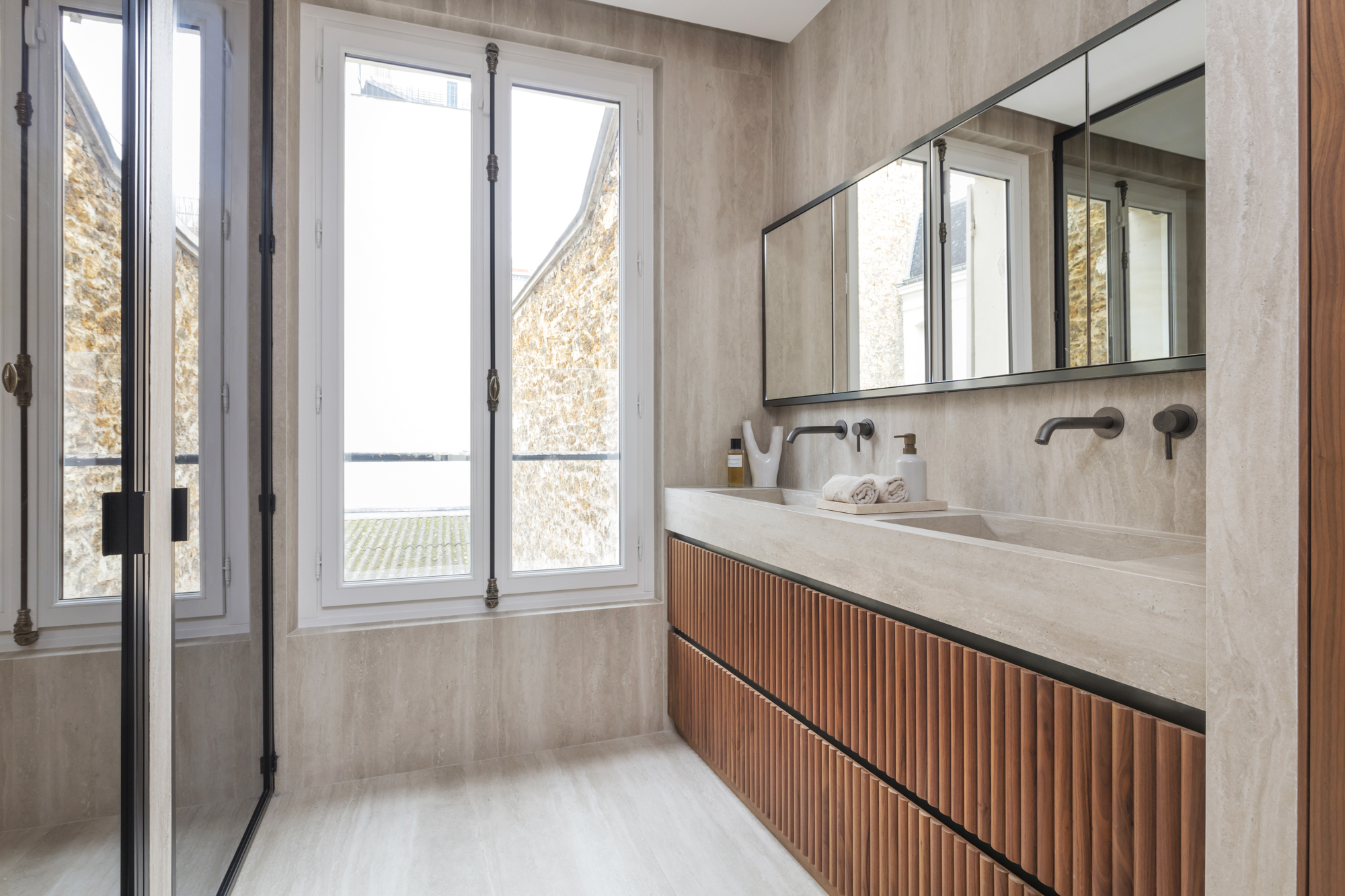 Salle de bain en pierre naturelle avec double vasque — conciergerie Ginta Paris